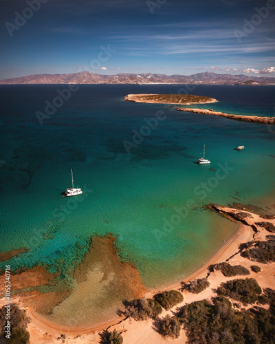Obraz na płótnie A serene beach on Paros Island, Greece, with golden sands, clear turquoise waters, and gentle waves. Framed by rocky cliffs and lush greenery, it's an idyllic Mediterranean escape under the sun. w salonie