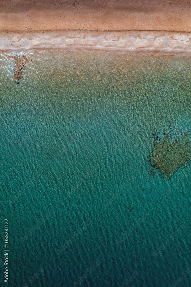 A serene beach on Paros Island, Greece, with golden sands, clear turquoise waters, and gentle waves. Framed by rocky cliffs and lush greenery, it's an idyllic Mediterranean escape under the sun.