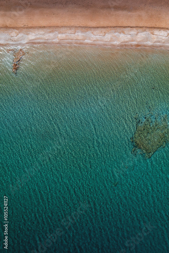 Obraz na płótnie A serene beach on Paros Island, Greece, with golden sands, clear turquoise waters, and gentle waves. Framed by rocky cliffs and lush greenery, it's an idyllic Mediterranean escape under the sun. w salonie