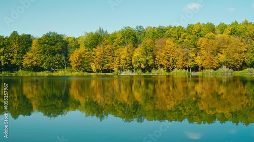 A view of forest on the edge of the lake,colorful trees reflecting in the water during sunny october day in Poland. photo