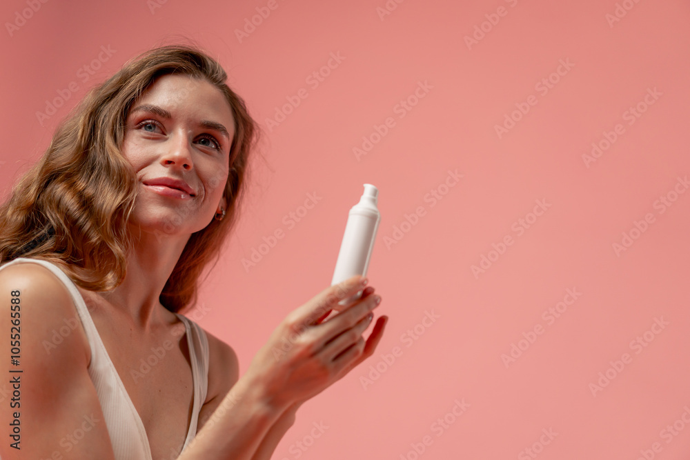 close up studio beauty shoot on pink background long-haired girl sitting posing in underwear with white tube of cream natural beauty close up studio beauty shoot on pink background long-haired girl sitting posing in underwear with white tube of cream natural beauty