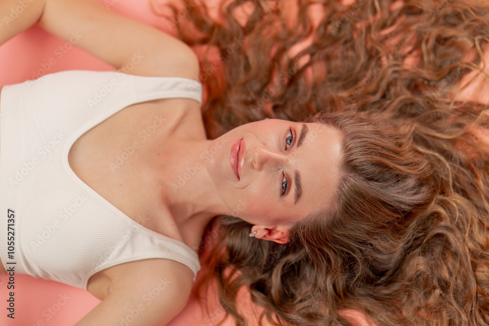 close-up studio beauty shoot on pink background beautiful girl lying in white underwear with loose hair natural beauty close-up studio beauty shoot on pink background beautiful girl lying in white underwear with loose hair natural beauty