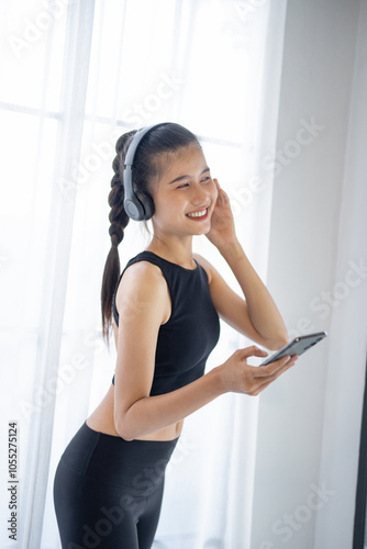 Fitness asian woman using smart phone and headphones Enjoy listening to music. Female with headphones smart phone after workout