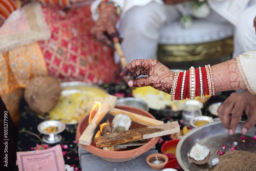 A Hindu ritual with offerings being made into a sacred fire, surrounded by ceremonial items and an open scripture. photo