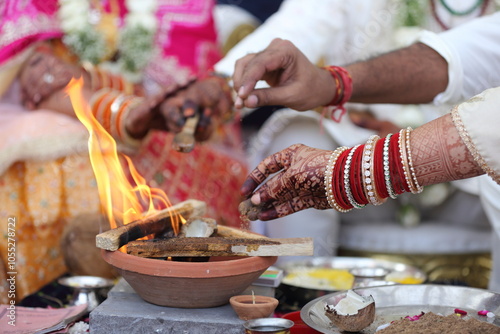 A Hindu ritual with offerings being made into a sacred fire, surrounded by ceremonial items and an open scripture. photo