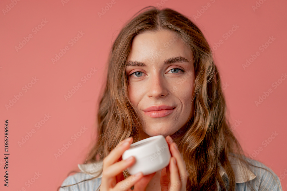 close up studio beauty shoot on pink background long-haired girl posing in underwear and blue shirt with jar cream natural beauty close up studio beauty shoot on pink background long-haired girl posing in underwear and blue shirt with jar cream natural beauty