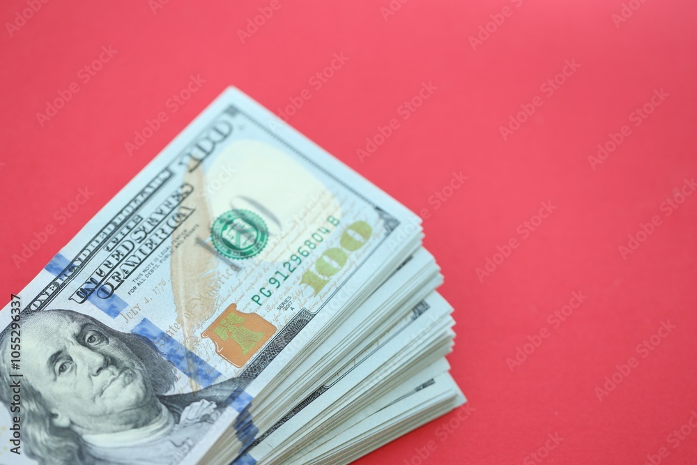Big amount of hundred dollar bills in thick stack lies on bright red color paper background Big amount of hundred dollar bills in thick stack lies on bright red color paper background