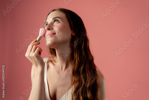 studio beauty shoot on pink background beautiful girl in white underwear standing with pink makeup brushes beauty salon smiling