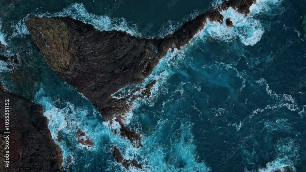 Immerse yourself in the raw beauty of the Atlantic Ocean as waves crash against the rugged rocks of Madeira Island, Portugal.