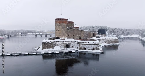 Panoramic drone shot around the snowy Olavinlinna castle, winter day in Finland photo