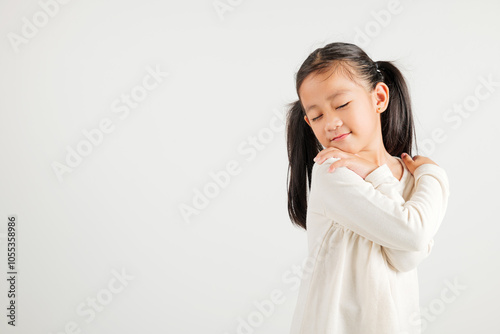 Happy young child smiling Asian girl hugging herself remember a moment studio short isolated on white background, Self care and self esteem concept, Lifestyle kindergarten kid love yourself carefree