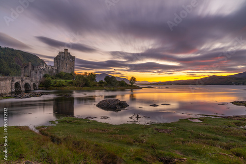 Eilean Donan Castle spiegelt sich bei Sonnenuntergang im Loch Duich, Langzeichtbelichtung erzeugt mit orangen und lila Wolken eine mystische Stimmung photo