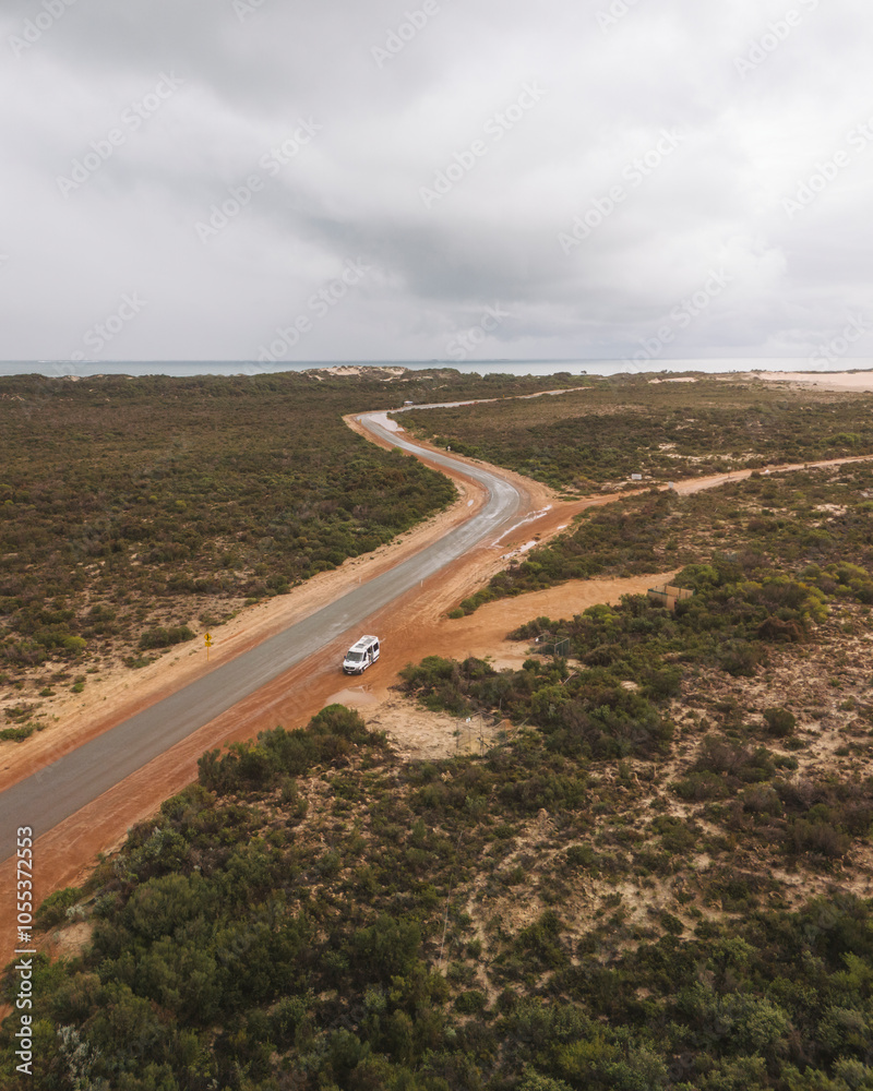 Aerial view of sandy cape with a winding road and serene bushland, Baie Jurien, Australia.