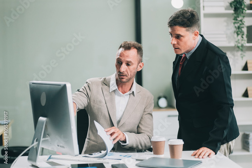 Two businessmen working together Analyze financial reports with charts and graphs while using the calculator to calculate budget, income, taxes, business growth. Startup business idea.