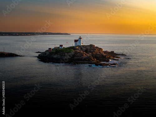 Aerial view of nubble lighthouse on a rocky coastline with tranquil ocean at sunrise, Cape Neddick, United States. photo