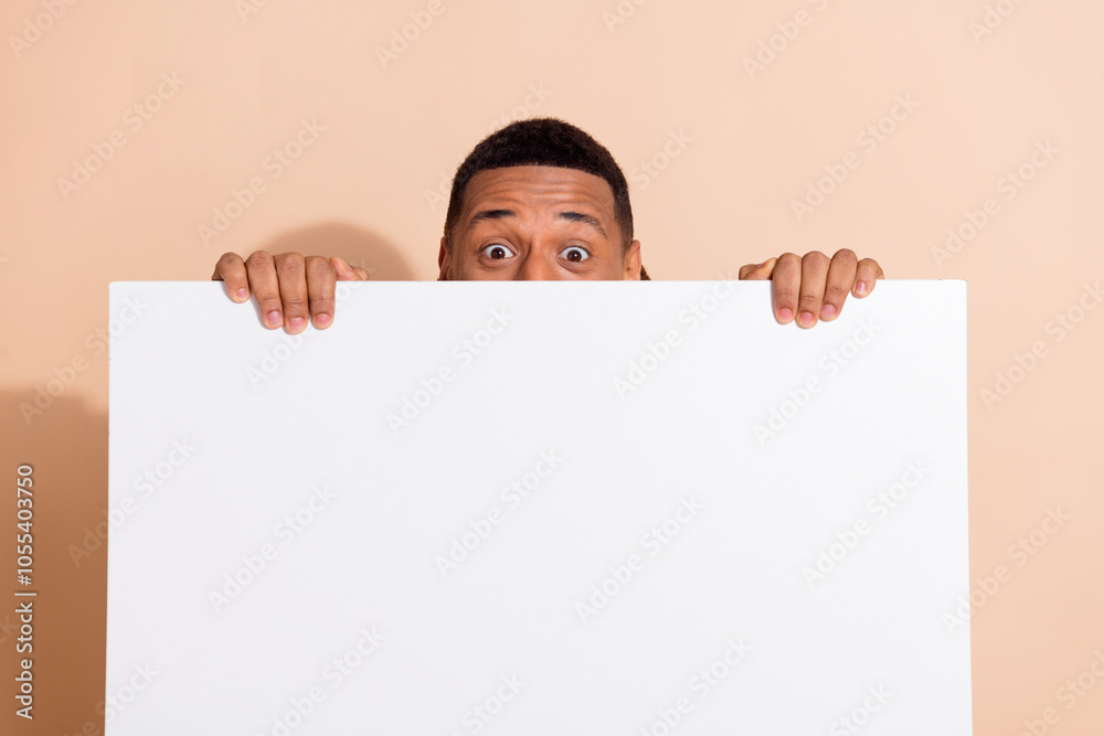 Photo of funky funny man wear trendy clothes hands hold empty space placard isolated on beige color background Photo of funky funny man wear trendy clothes hands hold empty space placard isolated on beige color background