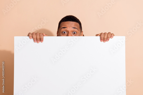 Photo of funky funny man wear trendy clothes hands hold empty space placard isolated on beige color background