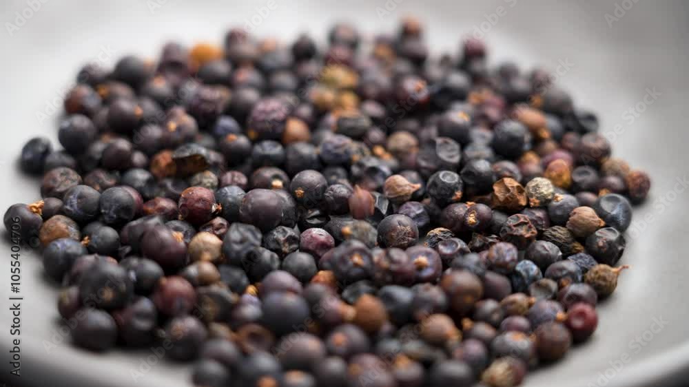 Dry Juniper berries falling on a gray plate as a rustic natural superfood used in traditional and contemporary health-focused diets. Slow motion. Rotation Dry Juniper berries falling on a gray plate as a rustic natural superfood used in traditional and contemporary health-focused diets. Slow motion. Rotation