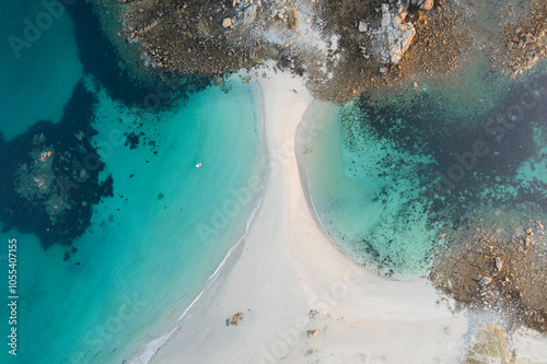 Aerial view of serene beach at sunrise with turquoise ocean waves and a boat, Cleder, France. photo