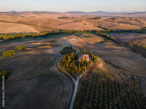 Aerial view of a small house on hilltop surrounded with vineyard at sunset in Val d'Orcia, Tuscany, Italy.