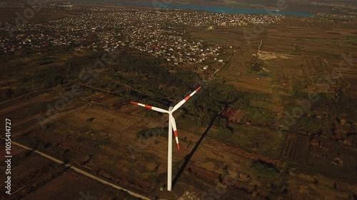 Aerial view of wind turbine generating green energy, between agricultural land. Drone footage.