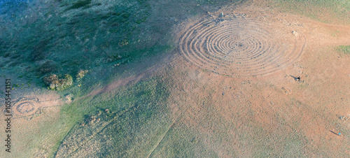 Aerial view of circular patterns in green grass fields at the archaeological site of Arkaim, Chelyabinsk Oblast, Russia.