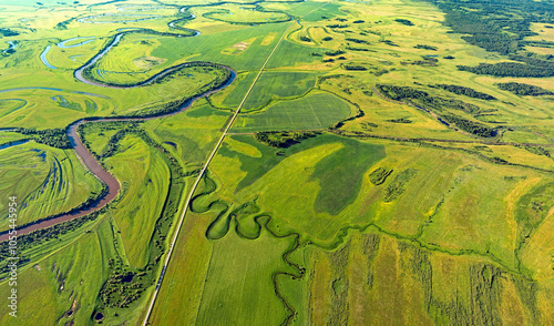 Aerial view of meandering river through lush green fields and textured wetlands, Omsk Oblast, Russia. photo