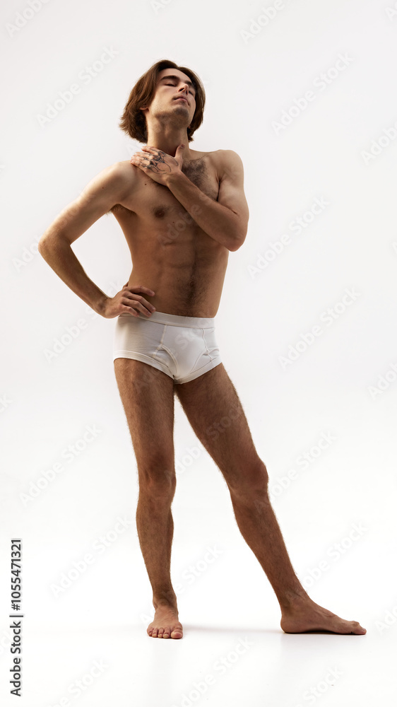 Elegantly posing young man in white underwear against white studio background. Man with athletic build body. Concept of natural beauty, male health, fashion, skin care. Ad Elegantly posing young man in white underwear against white studio background. Man with athletic build body. Concept of natural beauty, male health, fashion, skin care. Ad