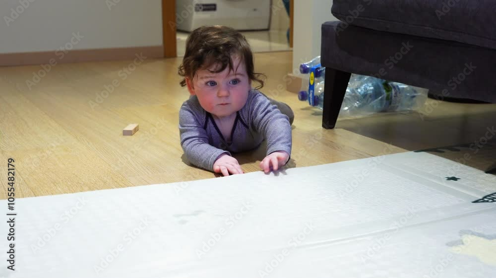 Seven month old boy with very thick dark hair lies on the floor and plays with a rug (193) Seven month old boy with very thick dark hair lies on the floor and plays with a rug (193)