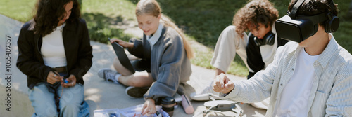 Website banner with boy playing VR game while his biracial friends building robots in background photo