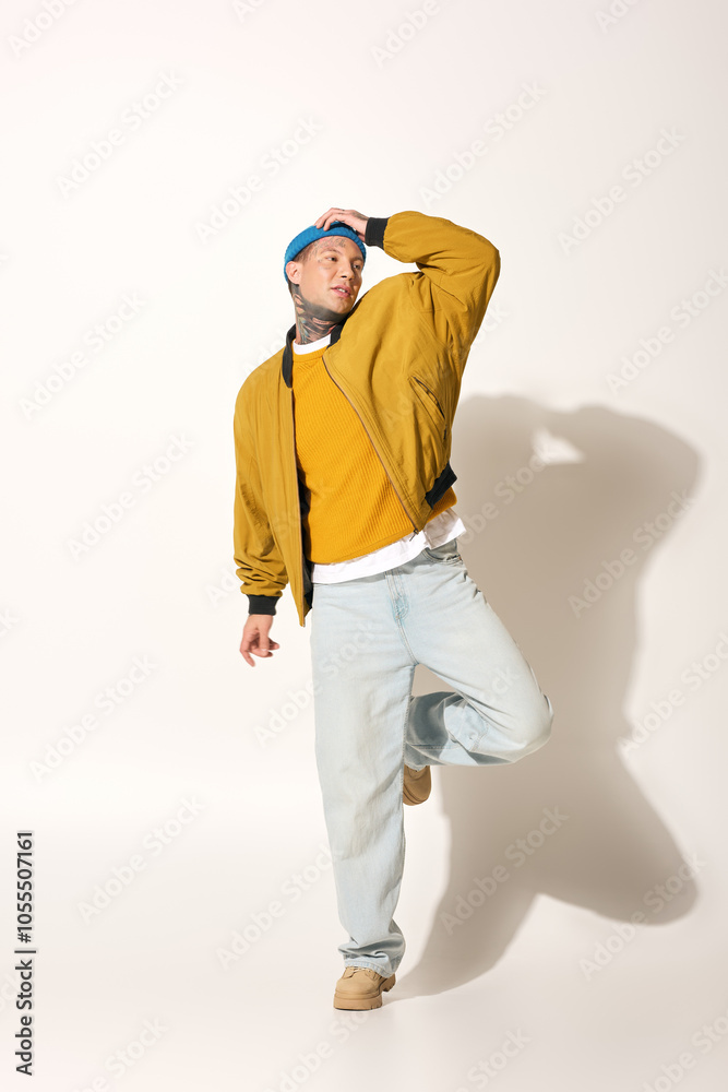 A young man showcases his tattoos while striking an artistic pose in casual attire. A young man showcases his tattoos while striking an artistic pose in casual attire.
