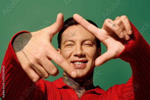 Fotografi The young man smiles widely, showcasing his tattoos while forming a playful gesture