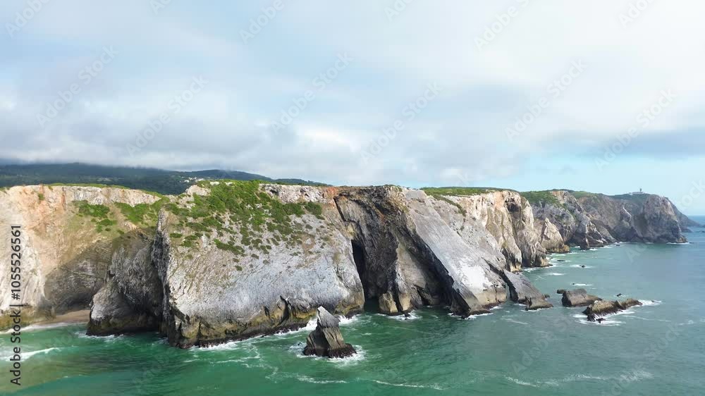 Wide drone panorama of the high rocky coast of the Atlantic Ocean in Sintra, Portugal. Adraga Beach, Ursa Beach. Blue water hits the rocky long shore. Wide drone panorama of the high rocky coast of the Atlantic Ocean in Sintra, Portugal. Adraga Beach, Ursa Beach. Blue water hits the rocky long shore.