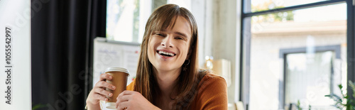 Joyful expression radiates as they sip coffee in the bright office space.