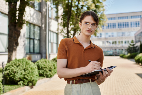 A non binary individual stands outdoors, taking notes on a clipboard while absorbing the sunlight. photo