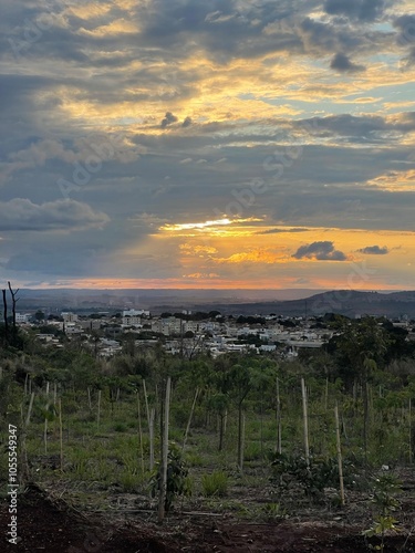 Pôr do sol com nuvens e parte da cidade mostrando um pedaço de reflorestamento numa reserva. photo