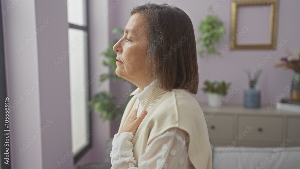 Mature woman standing thoughtfully in a cozy living room with stylish decor. Mature woman standing thoughtfully in a cozy living room with stylish decor.