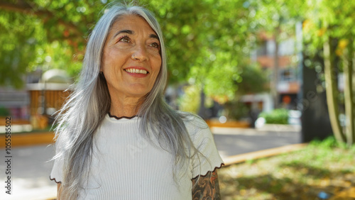 Elderly woman with grey hair smiling in an outdoor urban park on a sunny day. photo