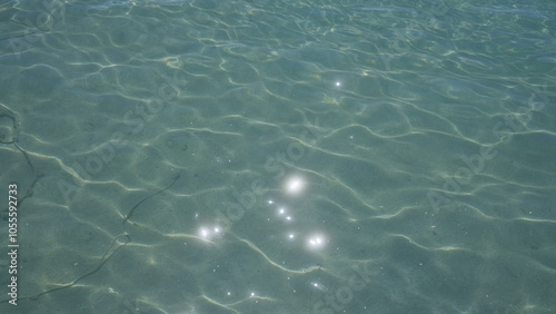 Sparkling sunlight reflects on the clear shallow water of the mediterranean sea in porto cesareo, italy, showcasing the serene and tranquil beauty of the salento coast in puglia