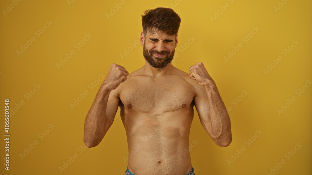 Shirtless young hispanic man celebrates with closed fists against an isolated yellow background, expressing joy and achievement Shirtless young hispanic man celebrates with closed fists against an isolated yellow background, expressing joy and achievement