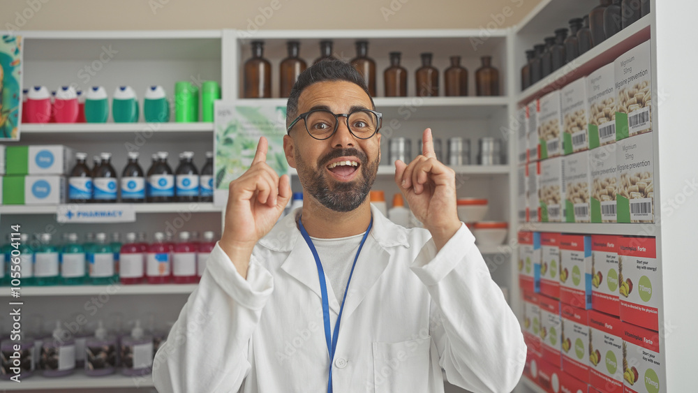 A smiling young hispanic male pharmacist pointing upwards in a white lab coat inside a modern pharmacy A smiling young hispanic male pharmacist pointing upwards in a white lab coat inside a modern pharmacy