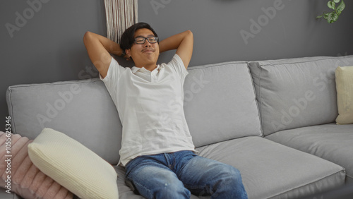 Young man relaxing on a couch in a modern living room at home, exuding a sense of comfort and ease