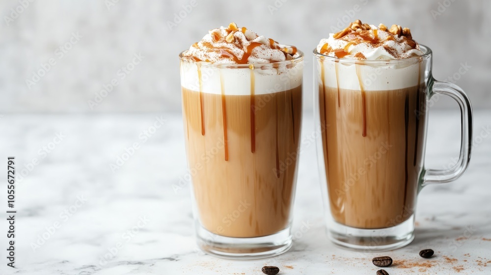 Two tall glasses of warm coffee topped with whipped milk foam cinnamon and caramel on a marble surface Two tall glasses of warm coffee topped with whipped milk foam cinnamon and caramel on a marble surface