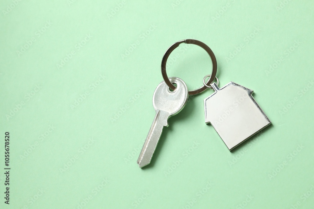 Metallic key with keychain in shape of house on color background Metallic key with keychain in shape of house on color background