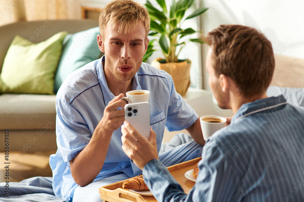 Obraz premium A loving gay couple relaxes together in their pajamas, sipping coffee