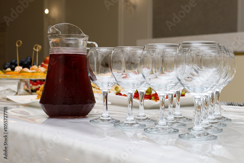 transparent glasses next to a jug of red wine