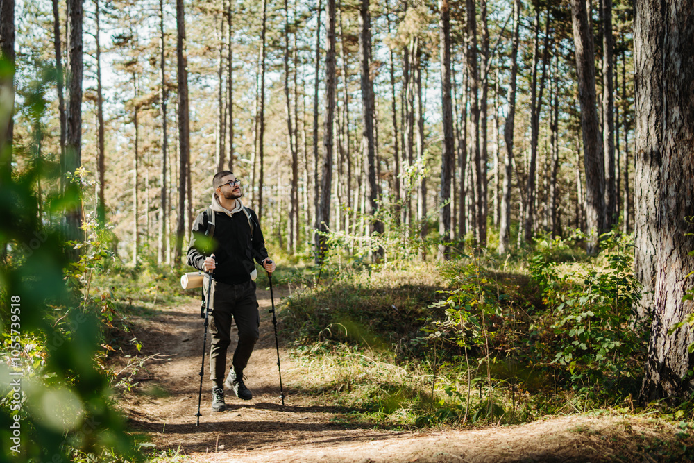 Young caucasian man hiking or trekking through the forest Young caucasian man hiking or trekking through the forest