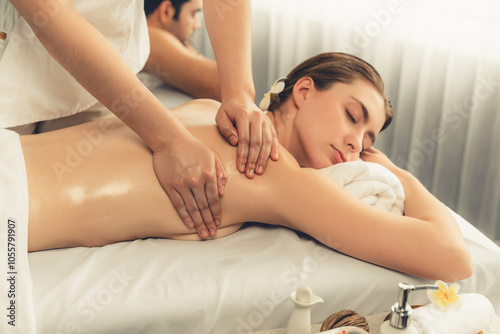 Caucasian couple customer enjoying relaxing anti-stress spa massage and pampering with beauty skin recreation leisure in day light ambient salon spa at luxury resort or hotel. Quiescent