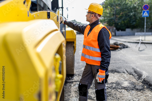 Construction worker inspecting heavy machinery on a road repair site during daylight in an urban area photo