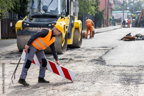 Tableau sur toile Construction worker setting up a traffic barrier during street repair in an urba